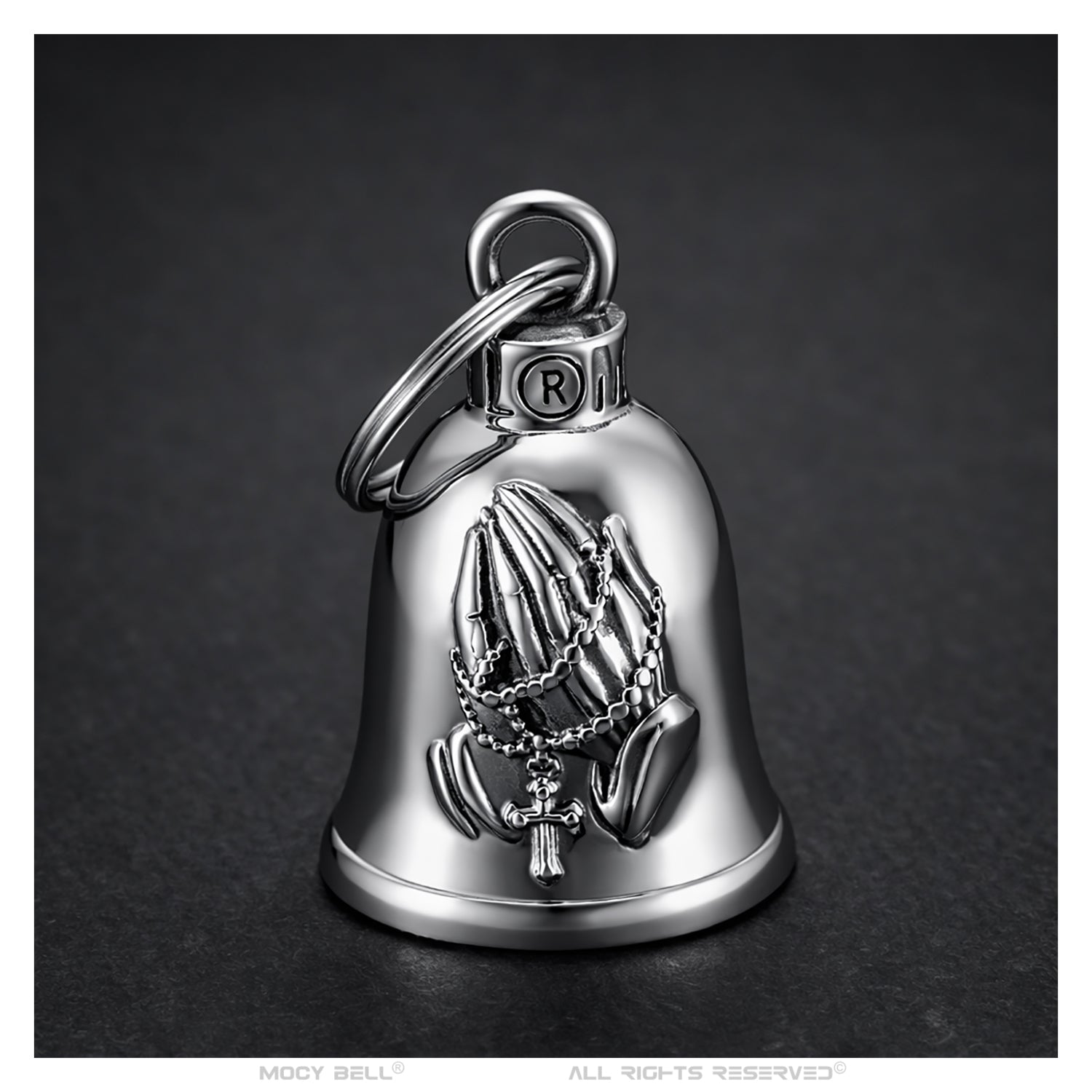 Sonnette moto acier photographiée de face, gravure mains en prière avec chapelet et croix visible sur fond blanc
